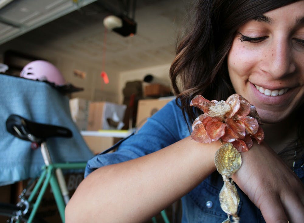 	Alexis Pavlantos models a necklace on Sunday that she made out of resin molding and a blooming  ower. All her jewelry is made with recycled materials. 