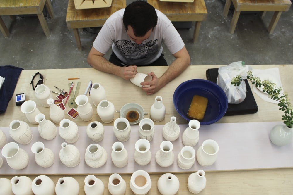 Ceramic artist Chris Casey works on his vases Sunday afternoon at the Arita Ceramics room for an upcoming art show. Casey sculpted 67 vases in total; 50 will be shown at the Harwood Art Center. 