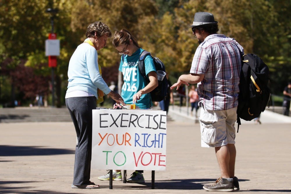 Anne Gordon Fritz, left, and Kylie Reeves, center, set the table with voting registration forms on Wednesday, Oct. 5, 2015 at Smith Plaza. New Mexico Public Interest Research Group went around campus to speak to students who were interested in registering to vote.