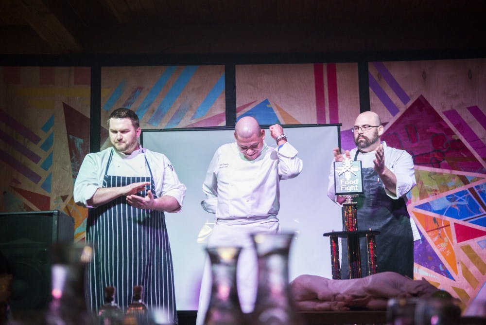 Chefs Colin Shane (left), Rafael Zamora (center) and Sean Staggs celebrate when their secret ingredients are revealed Thursday night at the Pueblo Harvest Cafe. The three chefs competed in a timed cooking battle with ingredients that where undisclosed to them prior to the event.&nbsp;