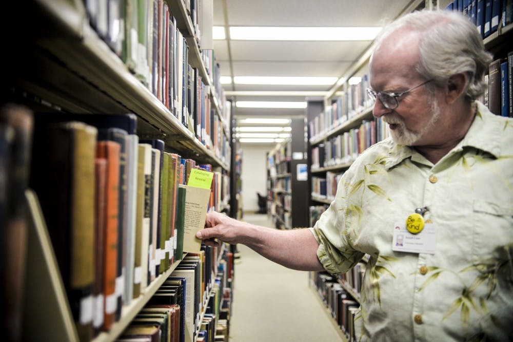 UNM Libraries Specialist Joseph Lane removes a book from the third floor of Zimmerman Library Tuesday August 23, 2016&nbsp;as he goes about his daily routine of cataloging. Lane has been in his position for 30 years and will be one of the many employees that will be affected by the Fair Labor Standards Act.