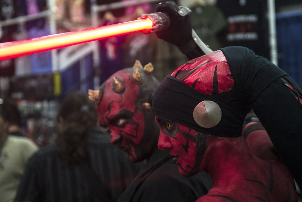 	P.I.G. Cosplay Group member Melissa King cosplaying as Darth Talon, right, lifts a lightsaber along with member Christopher Whyman cosplaying as Darth Maul during the Albuquerque Comic Expo on Friday. ACE 2014 included booths displaying extensive comic book, entertainment and pop culture memorabilia.