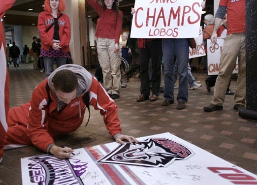 Phillip McDonald of the Lobo men's basketball team signs a poster at the Albuquerque International Sunport on Sunday after flying in from Wyoming. UNM fans packed the Sunport to welcome the Lobos, who beat the Cowboys at home Saturday to snag a share of t