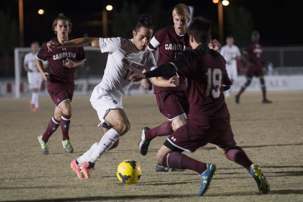 New Mexico midfielder Niko Hansen attempts to break free from South Carolina defenders during the game on Friday. The Lobos defeated the Gamecocks 2-1, earning the No. 5 seed for the C-USA tournament.
