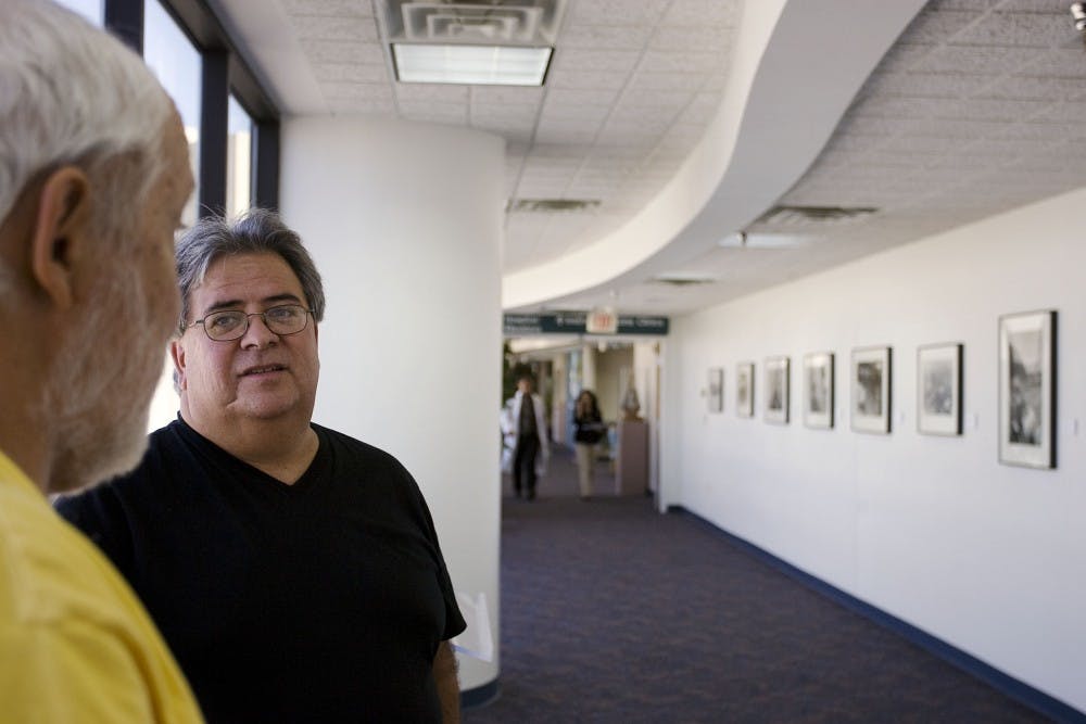 	John Abrams, left, and Professor Miguel Gandert talk at the Jonathan Abrams MD Art Gallery in the UNM Hospital. Gandert was the first artist to show his work at the gallery, which has hosted over 100 exhibitions.
