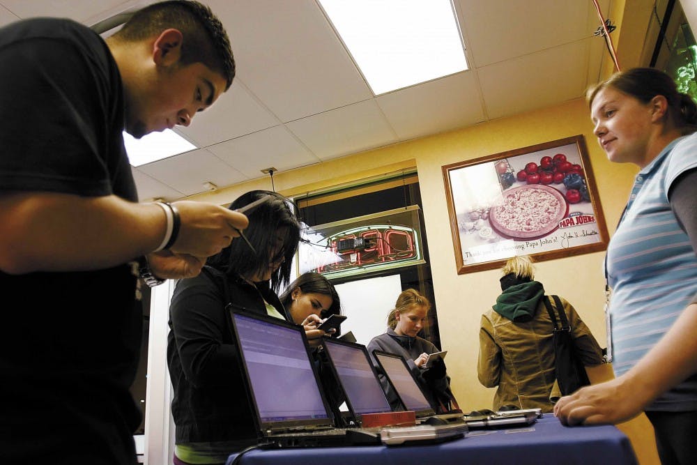 UNM freshman Michael Unzueta, left, enters personal information to determine his eligibility for an MTV Citibank credit card, while Elite Marketing employee Amy Morris, right, assists him during a promotion at Papa John's pizza on Central Avenue on Monday