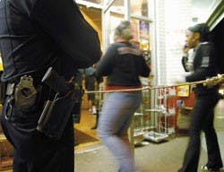 People walk through the door at Frontier Restaurant after being checked for weapons by private security early Sunday morning. Albuquerque Police officer ---Dan Peel, left, watches for criminal activity as a part of a city-sponsored service to keep Frontie