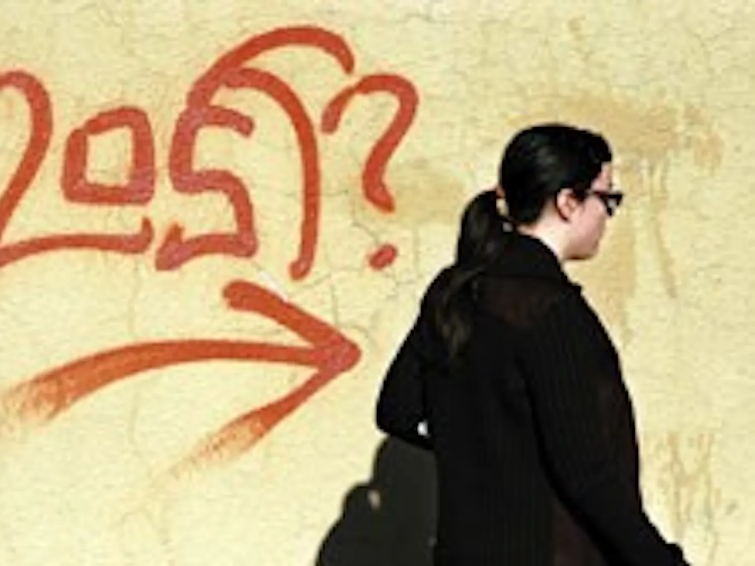 Student Kyla Worker walks by graffiti between Zimmerman Library and the SUB on Wednesday.