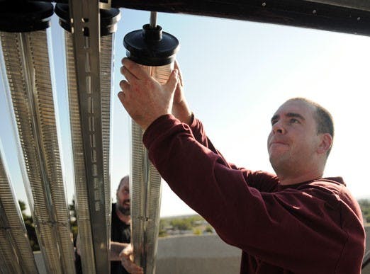 Dan Fisher, left, and Peter Vorobieff install a solar panel on top of the Mechanical Engineering Building on Tuesday. 