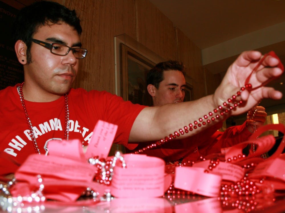 Mac Woods, left, and Brad Opatz prepare to hand out necklaces to lawmakers for UNM Day at the Capitol on Tuesday.