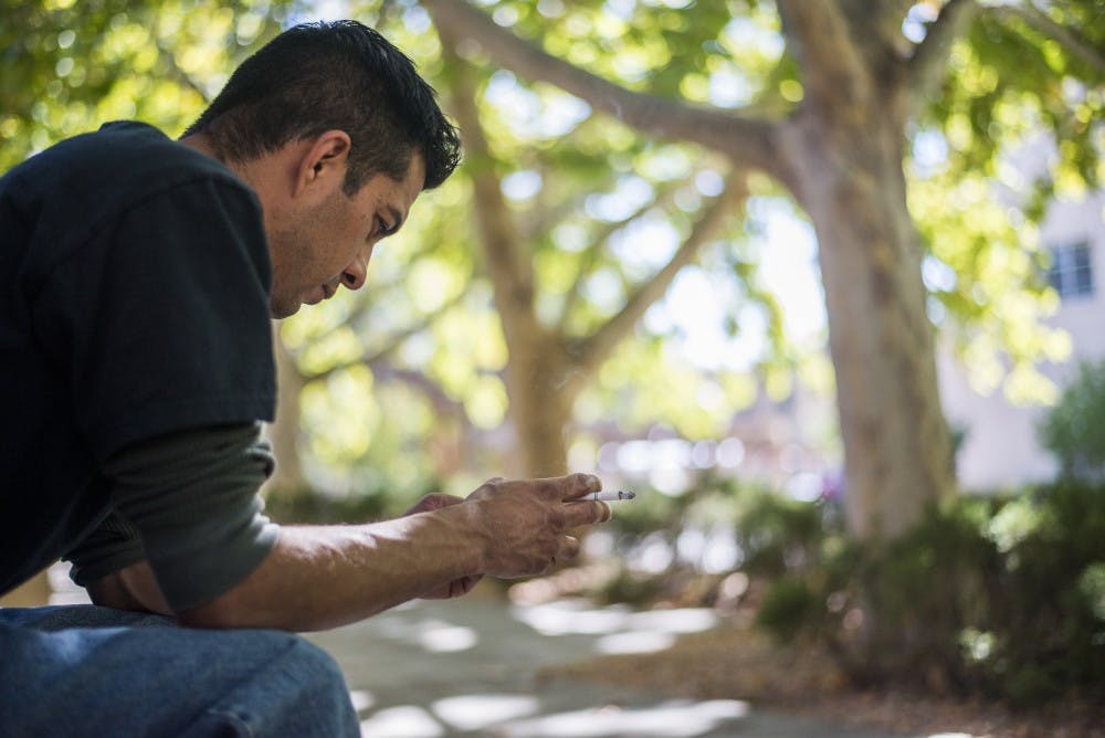Angel Cortez smokes at one of the designated smoking areas on Wednesday, Oct. 5, 2016 on UNM Main Campus. University administration plans to phase out all smoking areas on campus and begin fining smokers in fall 2017.&nbsp;