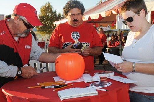 Mark Harwell, left, and John DeLorenzo, center, donate money to the United Way at President David Schmidly's tailgate party Saturday. Tracy West, right, works for the President's Office and collected the donations. 