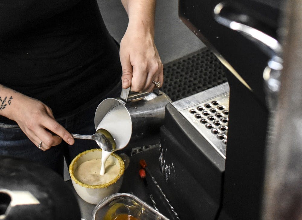 Danielle Bustos, co-owner of The Gathering Spot, makes a latte. Bustos has been with the cafe since its opening earlier this year.
