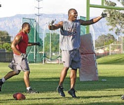 UNM defensive player Quincy Black, right, celebrates after a play during practice July 20 at the Lobo football practice field.