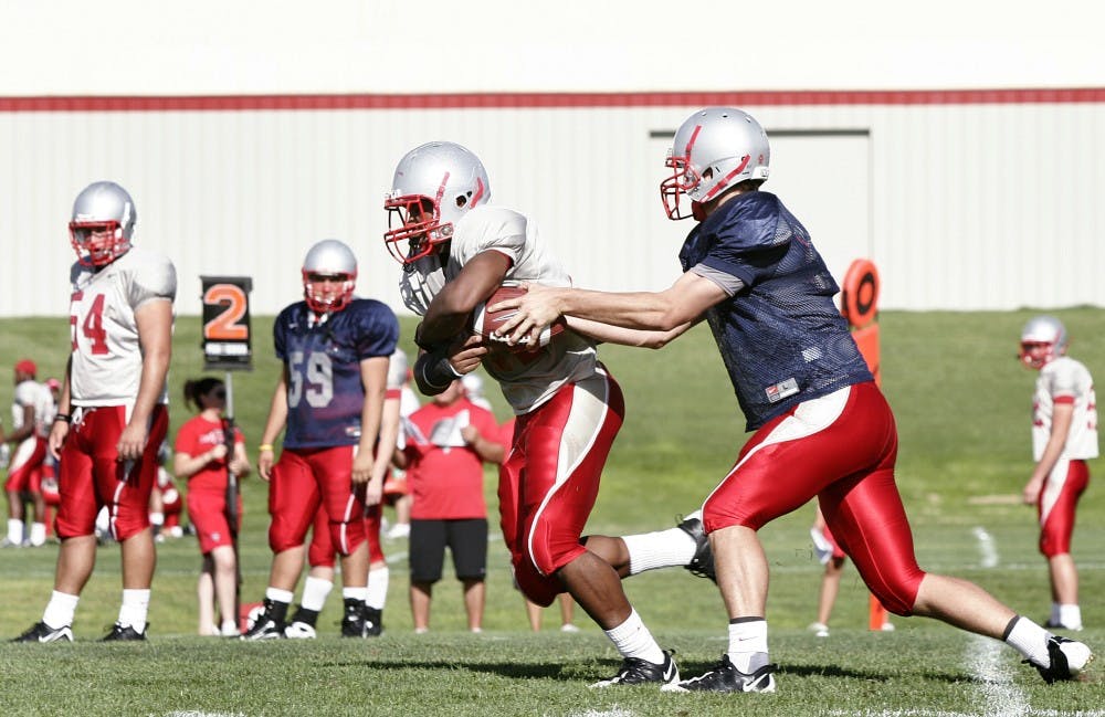 	Quarterback Brad Gruner, left, fakes a handoff to running back Kasey Carrier before dropping back to pass Wednesday at the UNM football practice facility.