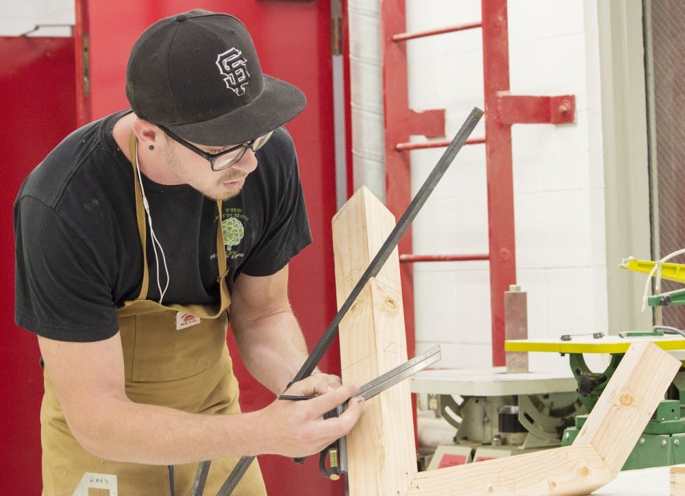 	Danny McCarthy, a senior dual major in art history and studio art, works on a project in the Fine Arts woodshop on Tuesday. McCarthy, along with other staff and students, has been affected considerably by the lack of funding to the Fine Arts department. 