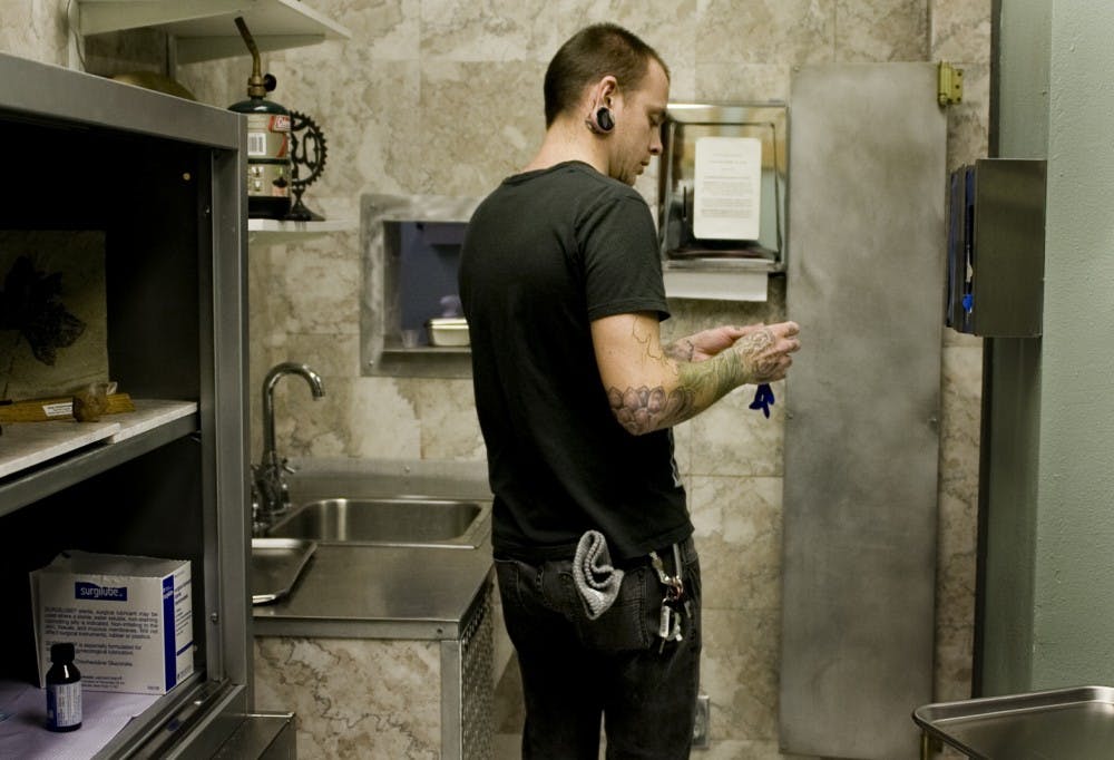 	Chris Jennell, body piercer at Evolution, Inc Body Piercing on Central Ave., stretches out a glove before getting to work on Monday.