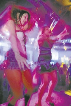 Students Francine Perez, left, and Valerie Griego dance at the Coliseum nightclub at 515 Central Ave. N.W. during a Mardi Gras party on Tuesday. 