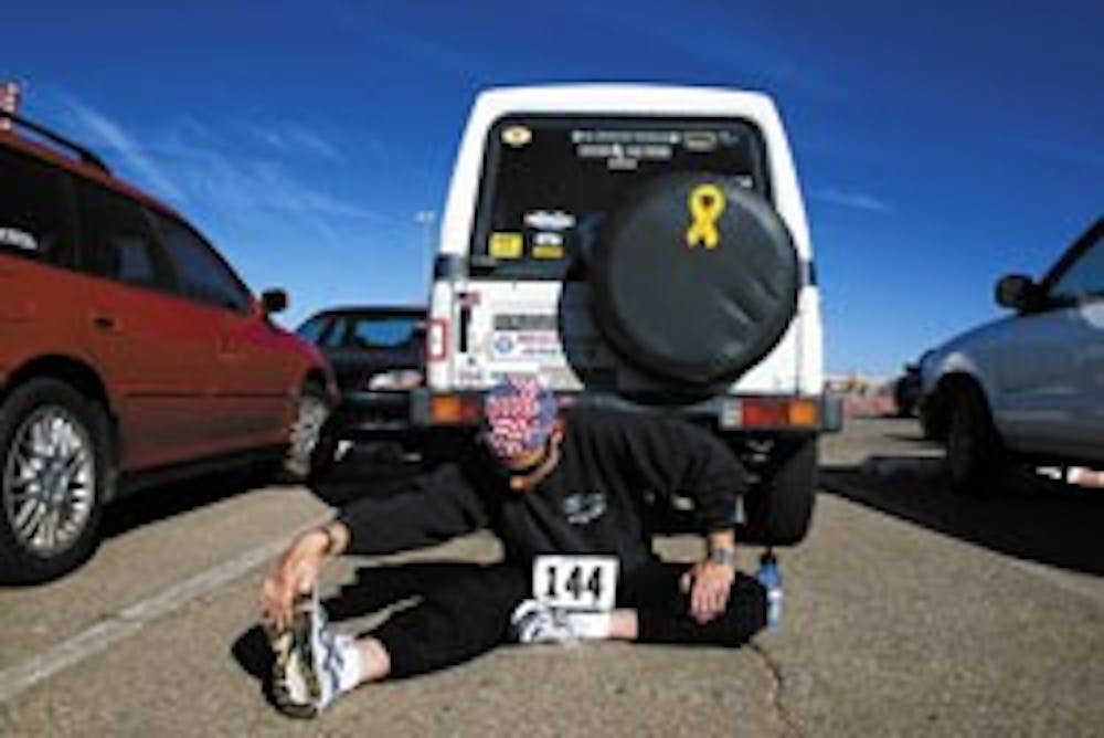 Ray Olesky, an employee for UNM Parking and Transportation Services, stretches in the parking lot before running in the Turkey Trot at The Pit on Saturday. Runners were encouraged to donate nonperishable food items for a charitable organization. Olesky is