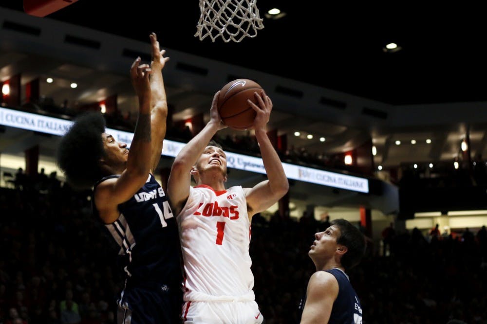 Redshirt sophomore guard Cullen Neal jumps towards the net past two Utah State players Jan. 9, 2016 at WisePies Arena. The Lobos...