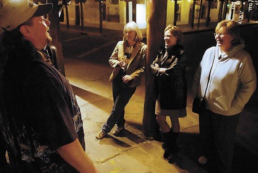 Bob Carter, a tour guide for the Ghost Walk of Old Town, left, talks to three visiting instructors from University of Texas-San Antonio, from left, Lauri Humberson, Carla Pennington and Mary Cottier about ghost sightings around Old Town on Monday.  