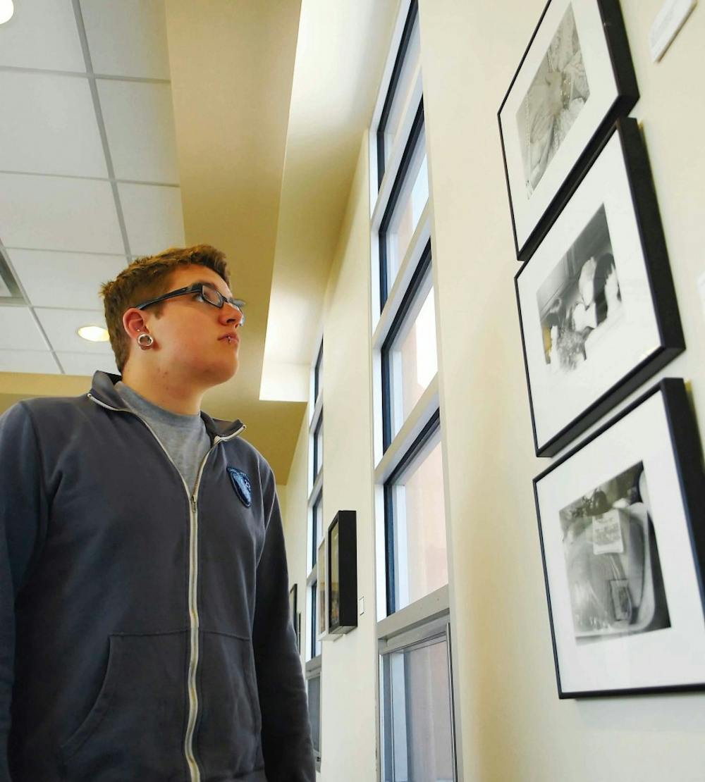 Max Jensen looks at photos in Molly Shannon's "Breast Cancer Survivors Collection" in the Cochiti Lounge on the third floor of the SUB.  