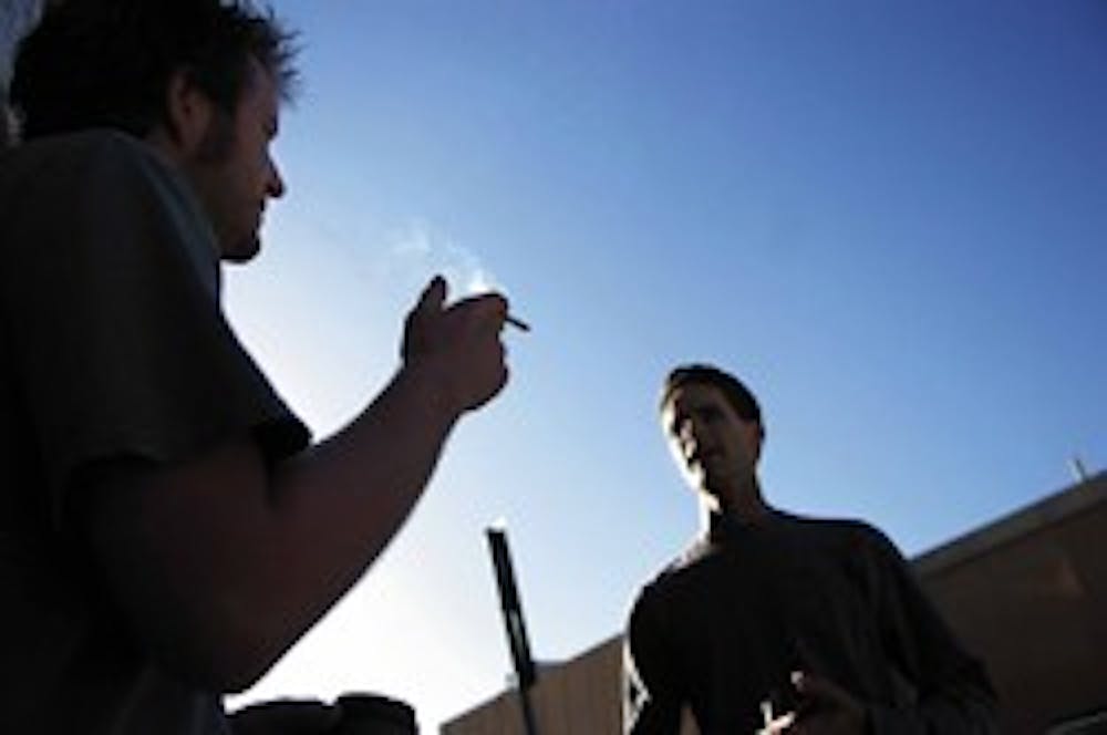 Billy Howell, left, smokes outside Marron Hall while having a conversation with non-smoker Allen C. Jones. The Coalition for a UNM Smoke Free Campus is petitioning to eliminate smoking on campus.