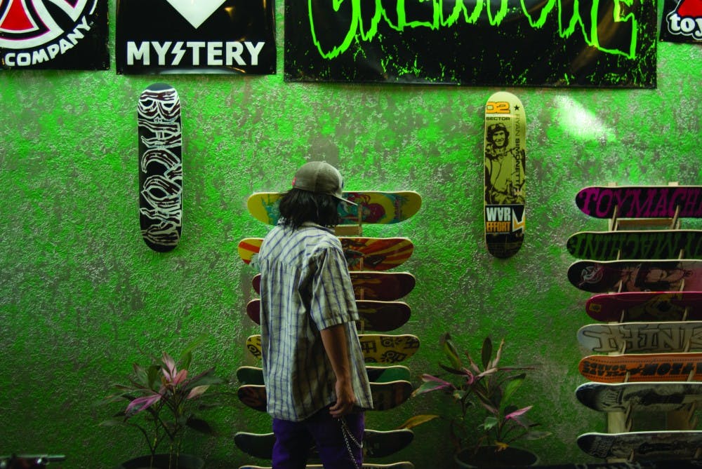 	Silver City Skate Shop employee Nigel Farell rearranges the wide selection of skateboards the store has for sale.