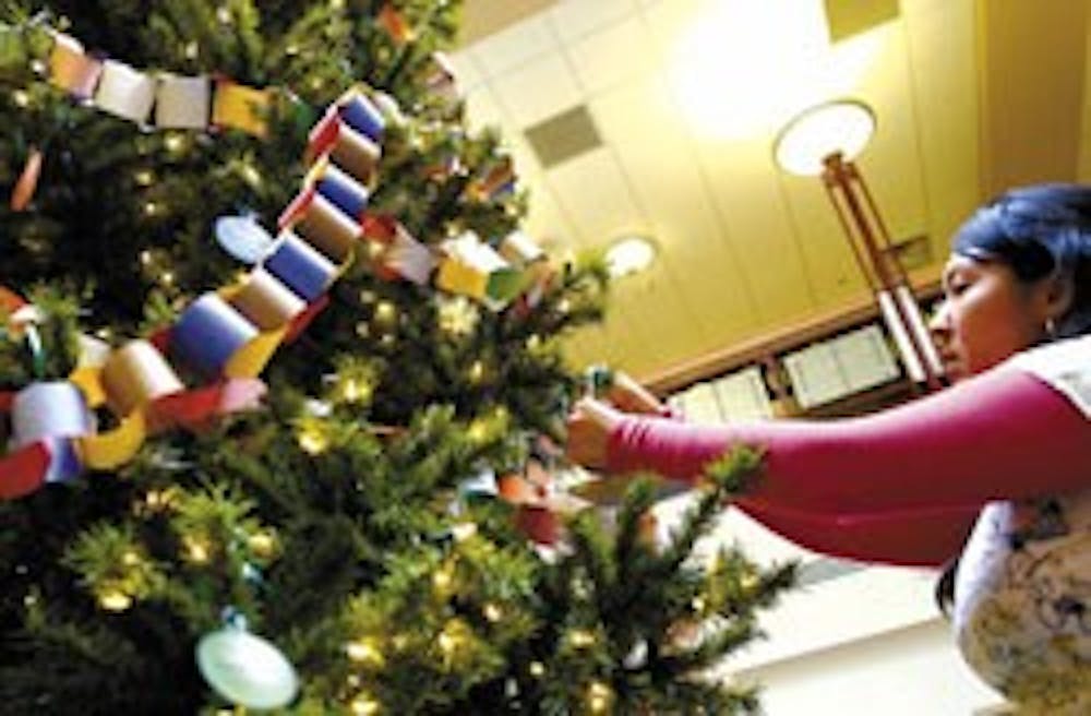 Margi Miranda, executive director of ASUNM Community Experience, decorates the UNM Giving Tree in the SUB Atrium on Tuesday. 