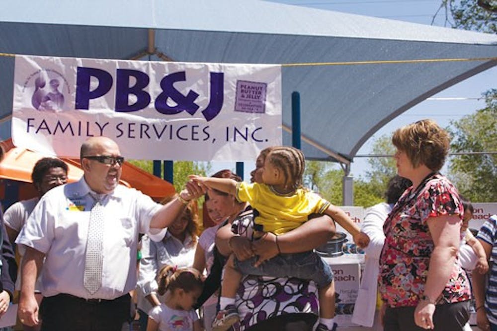 General manager of Wal-Mart on Rio Bravo, Max Torres, left, holds hands with Shanta Bausby's son during an event sponsored by PB&J Family Services Inc. at their headquarters on Monday. Wal-Mart and Wells Fargo donated money, food and Crock-pots to 100 fam