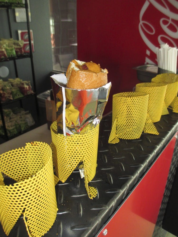 The finished Torpedo Dog, complete with red chile mustard in bread toasted from the inside, sits in a steel basket, ready for a customer. 