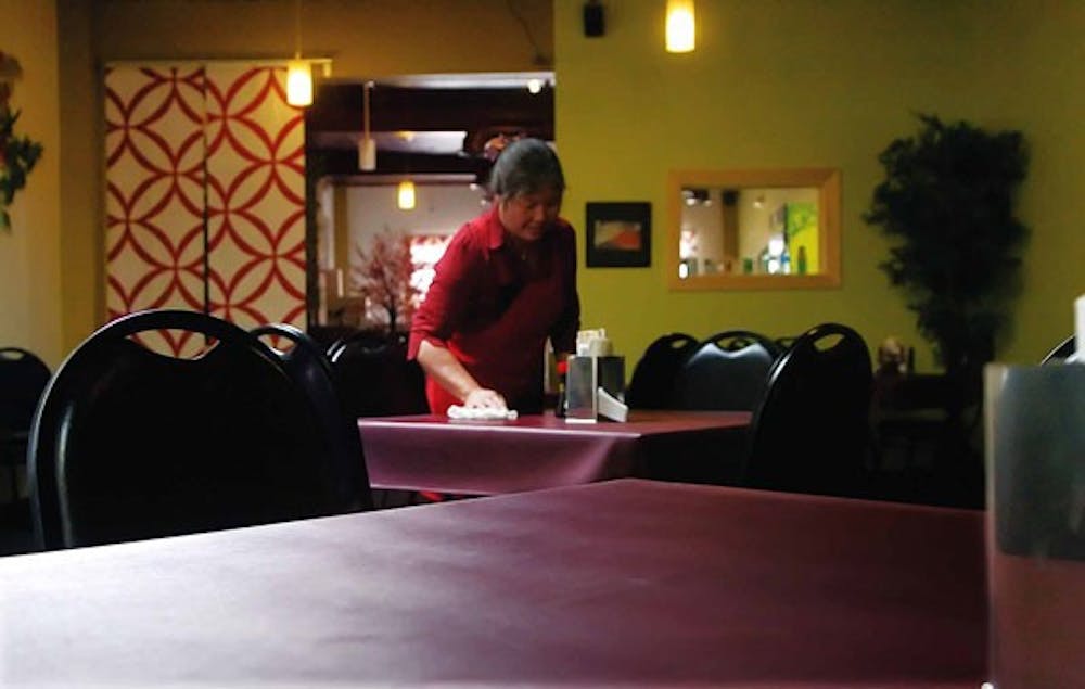 Light and Healthy Mirai Express manager Lily Genka cleans tables in the restaurant's empty dinning room June 22.  