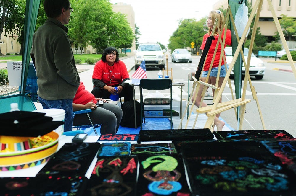 	From left: Bruce Milen, Frederico Jumbo and Shelby Spoonhoward sit and talk at the “Velvet Painting” parking space in front of the communication and journalism building on Friday. The Freshman Learning Community class “Earth Arts: People, Places &amp; Purpose” created this and four other spaces around campus to celebrate Park(ing) Day.