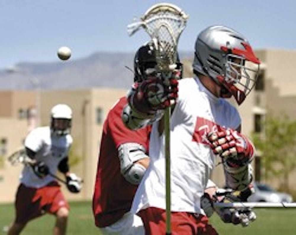 UNM lacrosse player Mike Mooney, right, fights with Wes Stallcup for the ball during a practice at Johnson Field on April 23.
