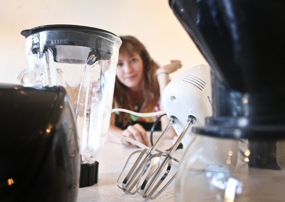 	In preparation for Friday’s show, artist Kristianna Smith contemplates the placement of kitchen appliances that will be displayed during the show, along with their corresponding video projections.