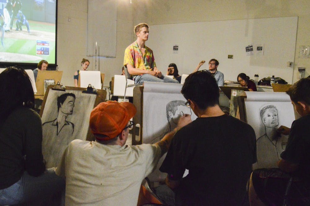 UNM instructor Sean Burke analyzes students’ techniques during a live model drawing&nbsp;class on Wednesday, Oct. 26 in the art building.