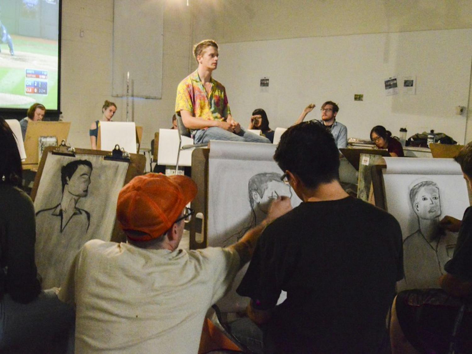 UNM instructor Sean Burke analyzes students’ techniques during a live model drawing class on Wednesday, Oct. 26 in the art building.