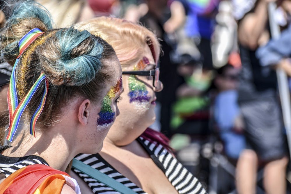 Two participants watch the parade pass by, wearing matching outfits and face paint.