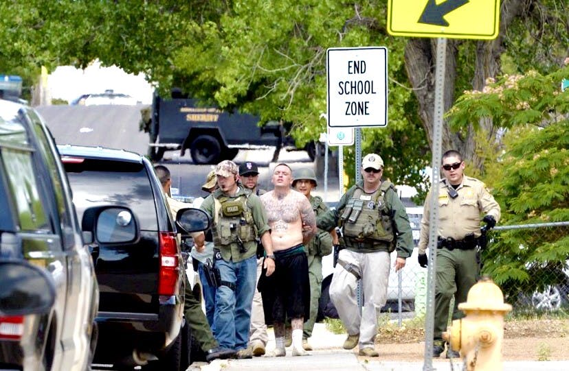 Albuquerque Police Department officers escort a man who locked himself inside his home after a warrant was issued for his arrest on&nbsp;Monday, June 27, 2016.