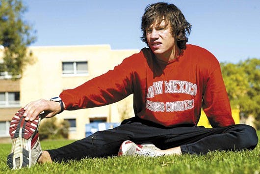 Cross country runner Nick Arguelles stretches on Johnson Field on Thursday. Arguelles was in an accident on his bicycle on Sept. 7 and ran his first meet of the season last weekend in Terre Haute, Ind., finishing fourth among the Lobo men's cross country 
