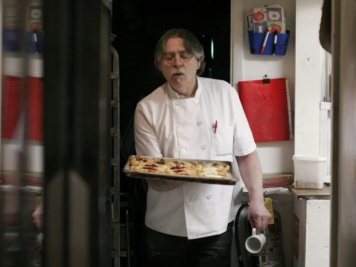 Gary Cline removes cherry and pecan Danishes from the oven at the Chocolate Cafe and Bakery on Monday.