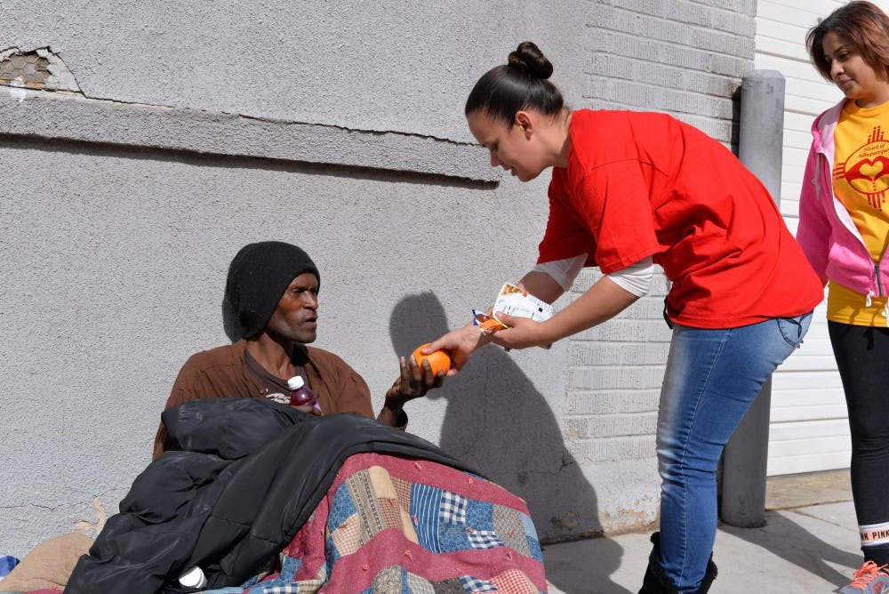 Homeless man receives an orange from Nicole Mestas during the Random Acts of Kindness walk.