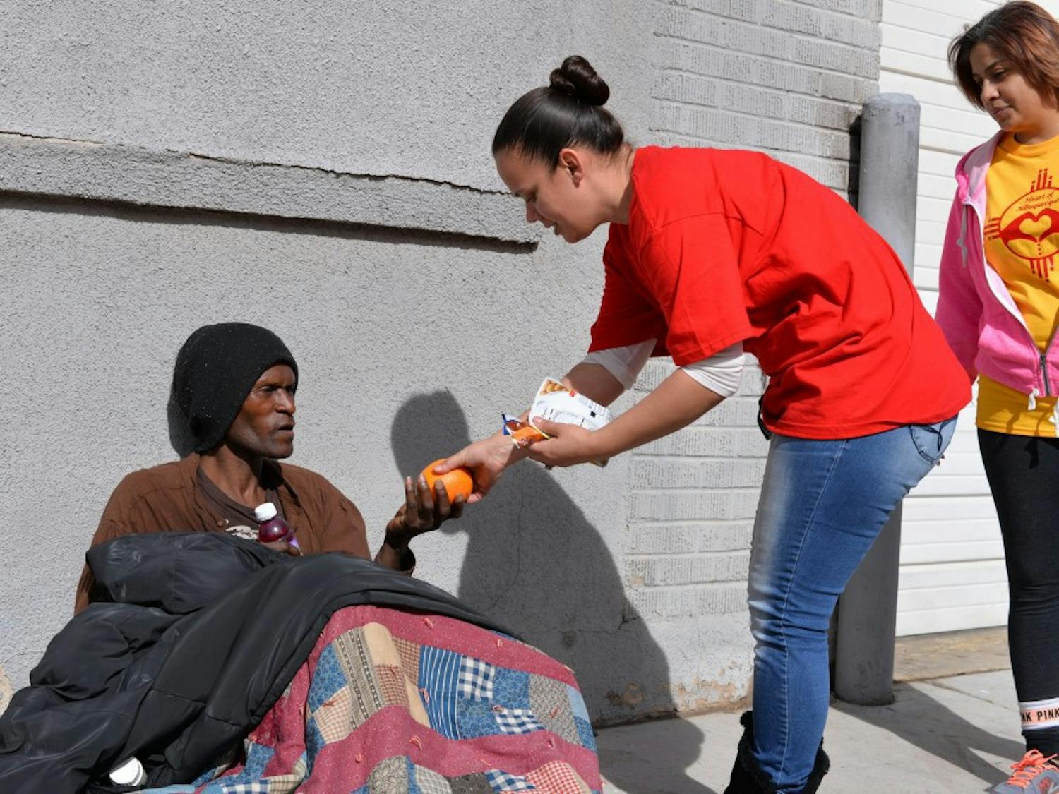Homeless man receives an orange from Nicole Mestas during the Random Acts of Kindness walk.