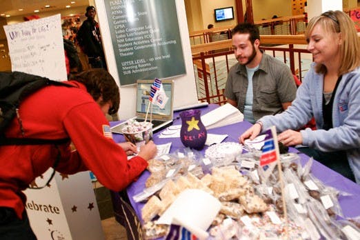 Student Matthew Buddrius, left, donates money - with help from Christian Garcia and Laura Rasmussen - to Relay for Life in the SUB on Tuesday.