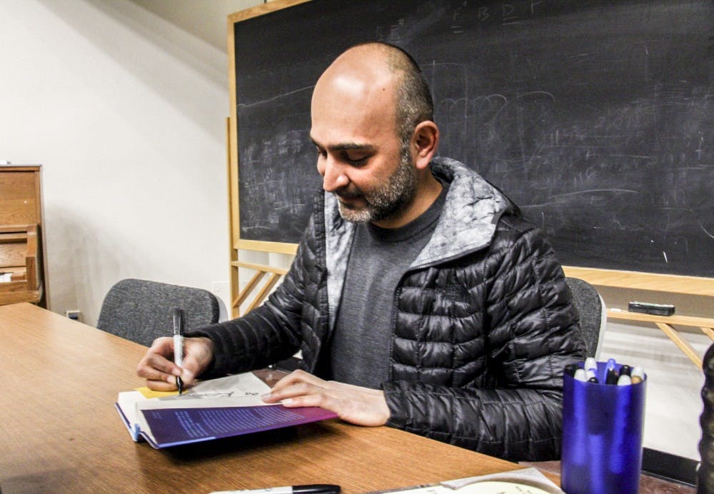 Author&nbsp;Mohsin Hamid&nbsp;sign an audience member's book&nbsp;after&nbsp;his presentation on April 3, 2018 at Woodward Hall.