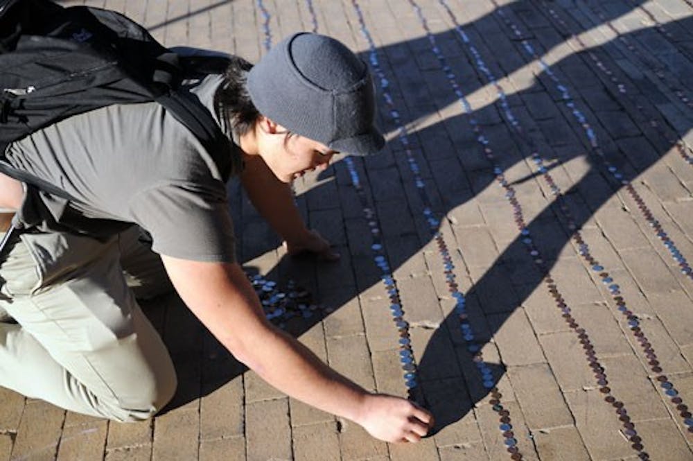 Sean DeBuck adds a penny to the Mile of Coins for a Veterans Day fundraiser in Smith Plaza on Tuesday. The donations were given to the Veterans Integration Center. 