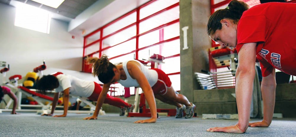 Jumper Hagit Salamon, right, does push-ups during indoor practice Tuesday. 