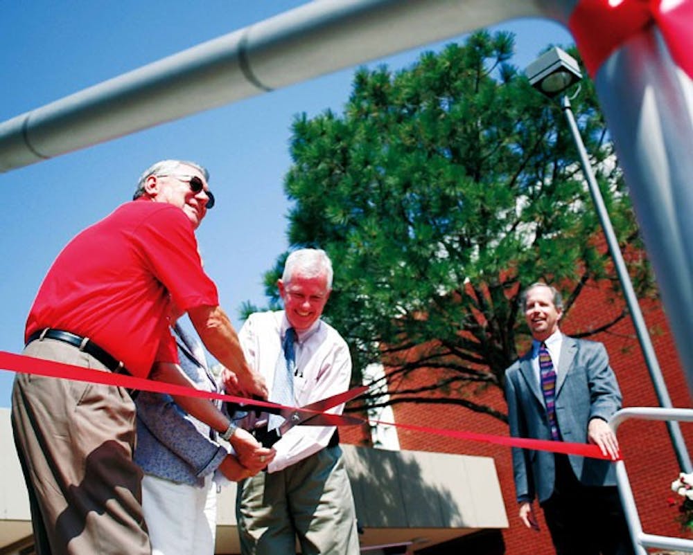 Chuck Fleddermann, associate dean of the school of engineering, watches UNM President David Schmidly, left, and Paul Broom cut the ribbon at a dedication ceremony for the Albuquerque Institute for Mathematics and Science charter school Friday.  