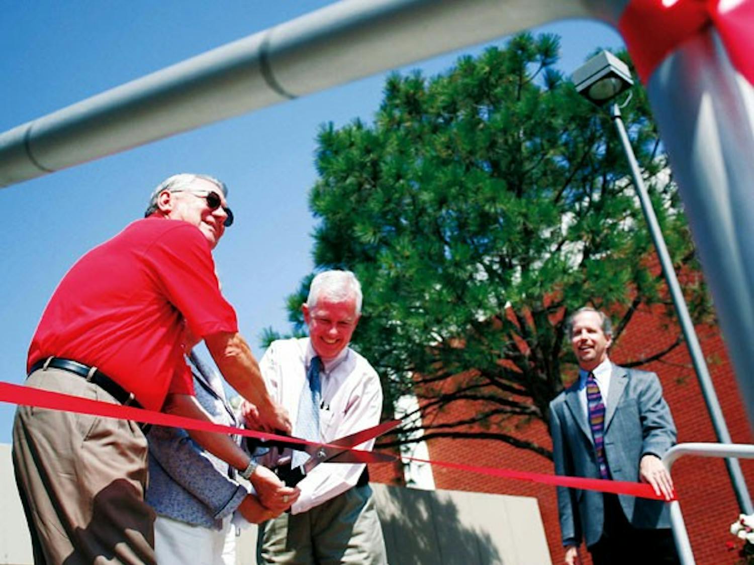 Chuck Fleddermann, associate dean of the school of engineering, watches UNM President David Schmidly, left, and Paul Broom cut the ribbon at a dedication ceremony for the Albuquerque Institute for Mathematics and Science charter school Friday.
