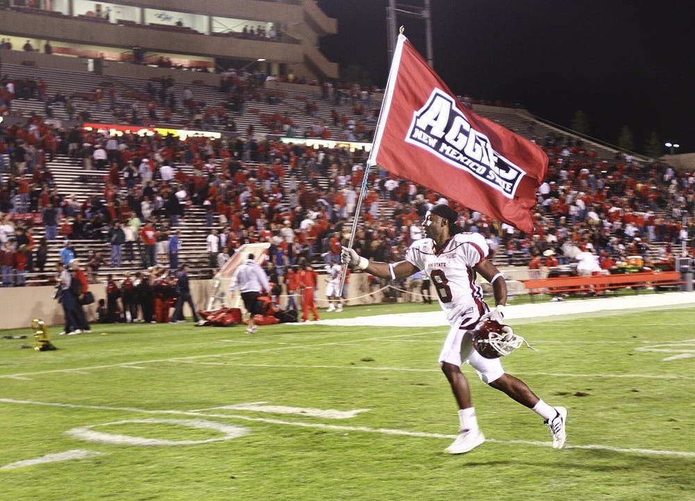 	NMSU cornerback Chris Buckner runs across University Stadium, proudly waving the Aggies’ flag. NMSU snapped a six-game losing streak to the Lobos, beating them 20-17. 